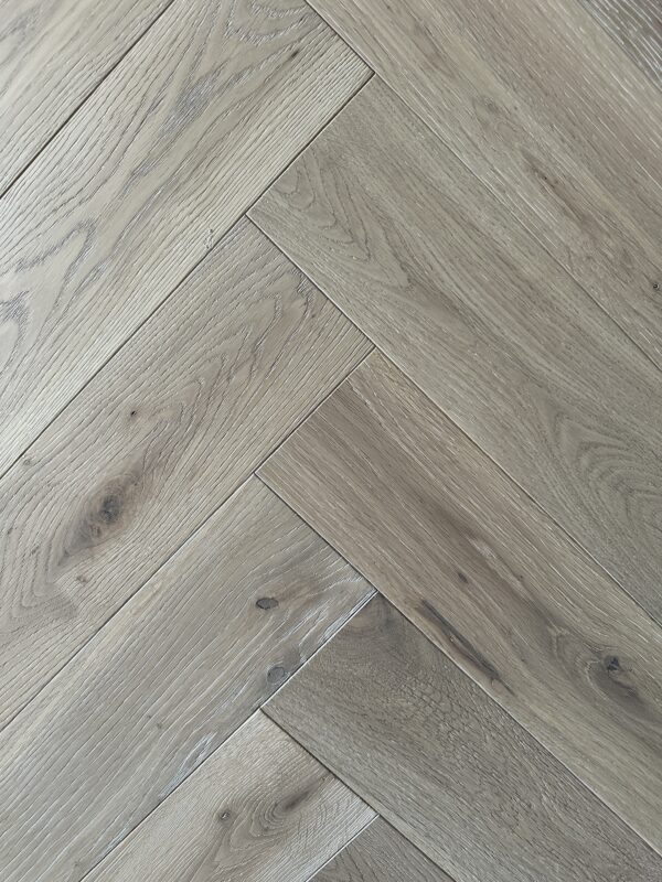 White smoked brushed waxed hardwood flooring, pale herringbone wood grain close-up Artisan Sienna Oak Brushed & Wax Oiled Herringbone 14/3x125x600mm Engineered Wood Flooring