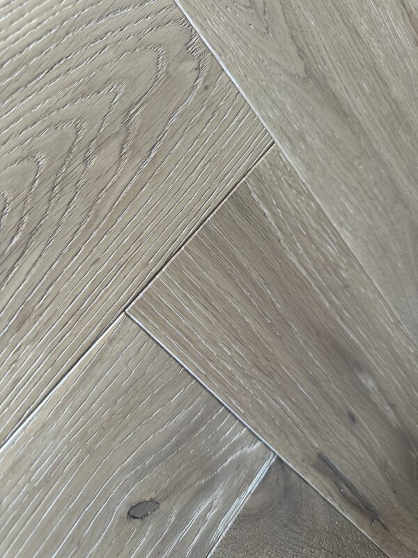 White washed herringbone hardwood flooring, close-up wood grain detail Artisan Sienna Oak Brushed & Wax Oiled Herringbone 14/3x125x600mm Engineered Wood Flooring